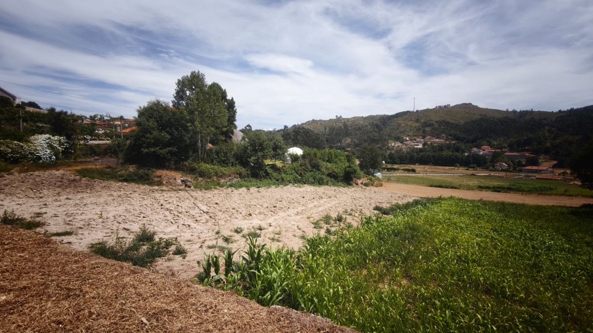 Terreno lavrado na área da aldeia, com casario de granito e o monte ao fundo