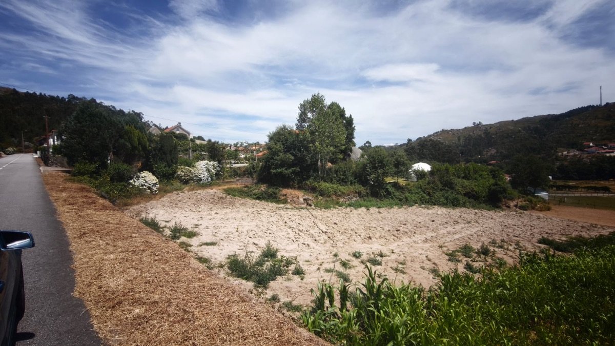 Área da aldeia vista da estrada, com o terreno lavrado e as casas vizinhas