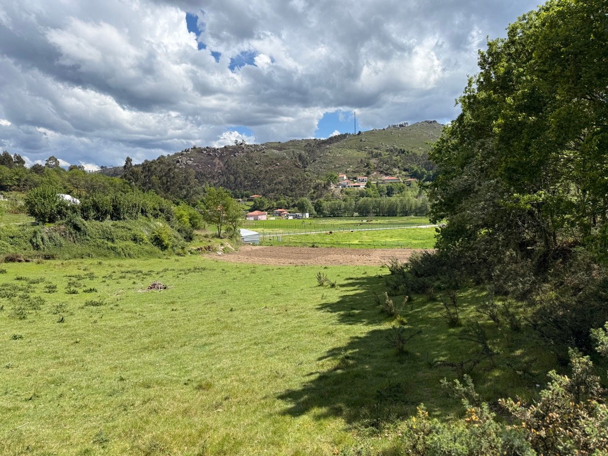 Pastagem e vale com aglomerado rural ao fundo, perto da propriedade